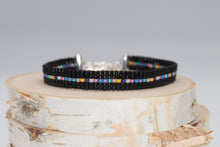 Load image into Gallery viewer, dainty black seed bead bracelet with a row of rainbow beads down the middle
