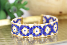 Load image into Gallery viewer, handmade seed bead bracelet in a cobalt blue, gold, and pearly white evil eye pattern. adjustable with a lobster claw and chain closure
