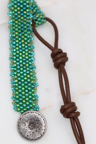 hand woven seed bead bracelet in an emerald green AB finish with a miyuki delica picot edge.  Adjustable leather loop and button closure