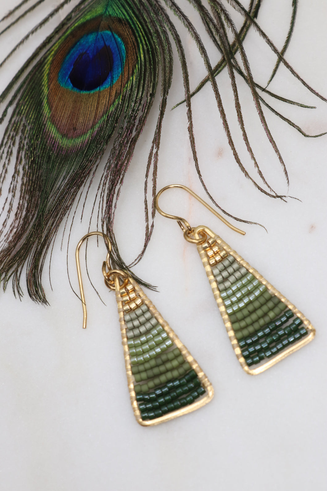 Lightweight hand beaded boho earrings made from golden brass triangles with premium delica seed beads strung horizontally inside in an ombre pattern from gold at the top through olive and avocado greens 