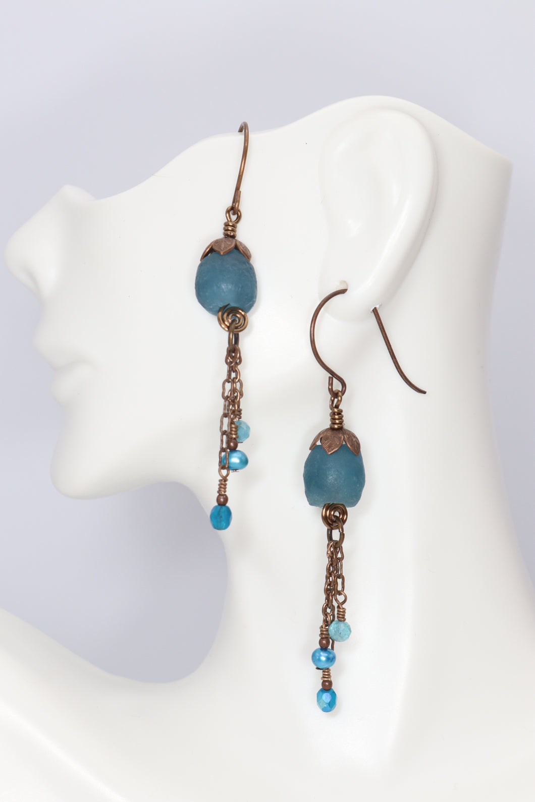 teal recycled glass beads accented with detailed petal like antiqued brass bead caps with chain dangles hanging from brass spirals.  The dangles feature dainty apatite, freshwater pearls & Czech glass
