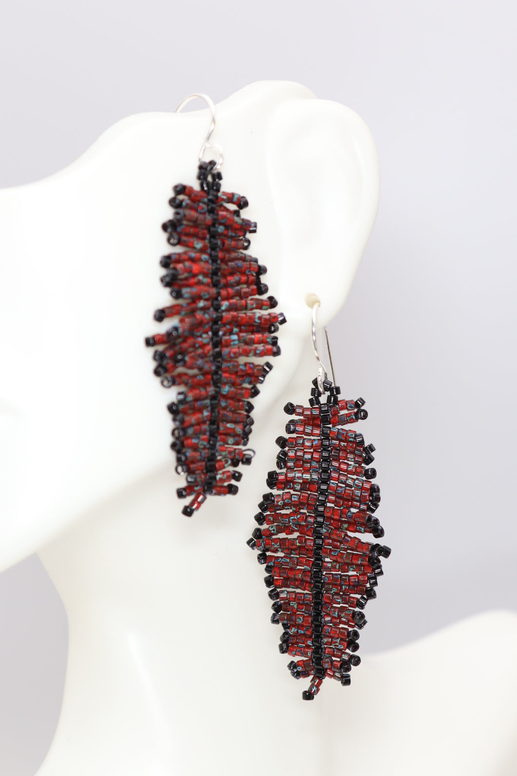 Handmade seed bead feather dangle earrings made from red Picasso seed beads with flecks of gray and turquoise accented with black.  hung on sterling silver wires.  