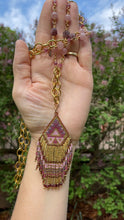 Load and play video in Gallery viewer, Boho long beaded necklace with a hint of southwest spice featuring a gorgeous hand beaded seed bead fringed pendant in shades of pink, purple, mauve, gold &amp; burgundy.  the pendant has tiny garnets at the ends of the fringe along the bottom of the pendant. The necklace consists of chunky brass chain accented with natural round &amp; star cut strawberry quartz, and faceted pink tourmaline cubes.  38 inches long. could be shortened upon request. 
